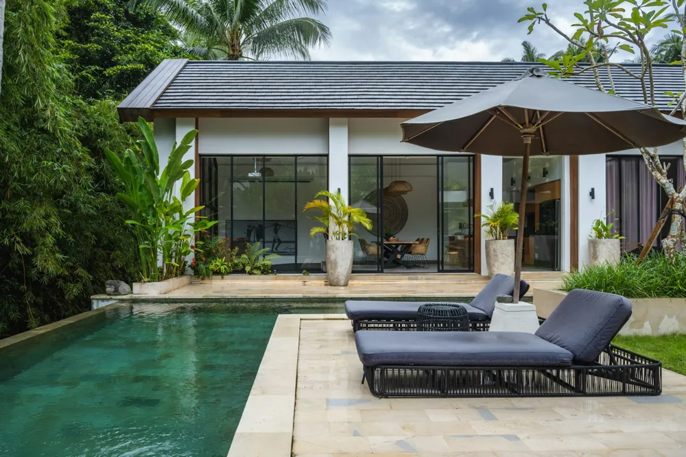 Piscina privada y terraza junto a una villa tropical moderna