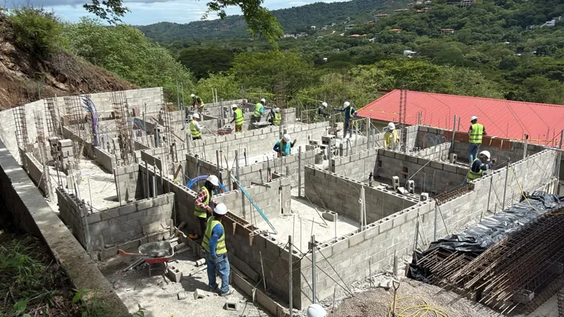 Vista amplia de la obra de Serena con paredes de bloque de concreto levantándose y trabajadores sobre la losa
